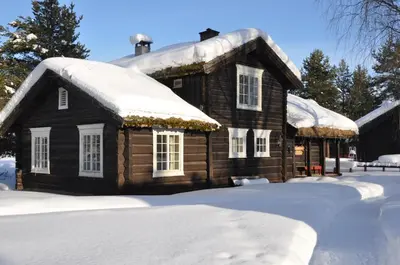 a log cabin with snow on its roof at Stor-Elvdal Hotell in Koppang