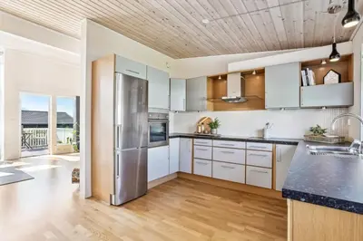 a kitchen with white cabinets and a stainless steel refrigerator at Moderne rekkehus nært Ålesund in Valderøya