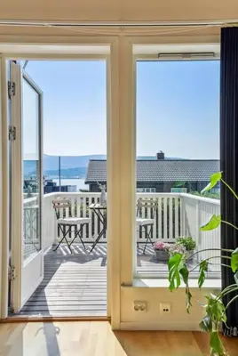 an open door to a balcony with a view of the ocean at Moderne rekkehus nært Ålesund in Valderøya