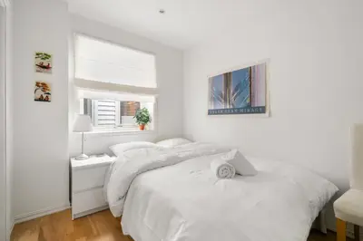 a white bedroom with two beds and a window at Scandinavian Hideaway I Private Balcony in Bergen
