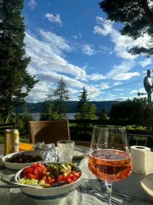 a table with a plate of food and a glass of wine at Family Cabin With Panoramic Views Of Tyrifjorden in Nes