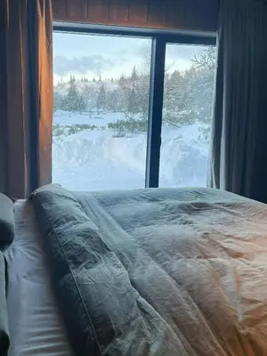 a bed in front of a window with snow outside at Architect Designed Mountain Cabin At Kvitfjell in Favang