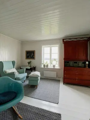 a living room with blue chairs and a window at Peaceful Log Cabin By The Fjord On Ytterøy in Ytteroy