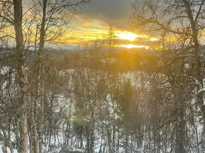 a sunset over a body of water with trees at Mountain Cabin With Panoramic Views In Savalen in Tynset