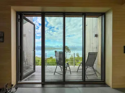 a screened porch with two chairs on a deck at Architect-Designed Cabin With View In Molde in Røvik