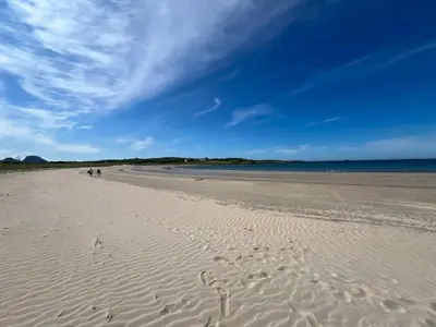 a beach with people walking on the sand at Architect-Designed Cabin With View In Molde in Røvik