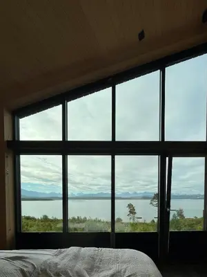 a bedroom with a large window looking out at the water at Architect-Designed Cabin With View In Molde in Røvik