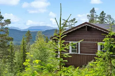 a cabin in the woods with mountains in the background at Cosy Cabin With Annex At Blefjell in Kongsberg