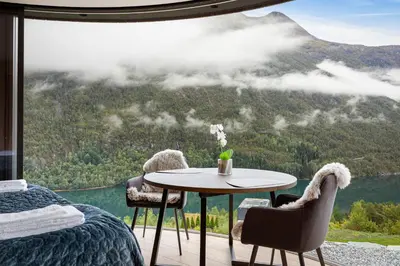 a room with a table and chairs and a view of a mountain at The Sognefjord Cabin 2 in Kaupanger
