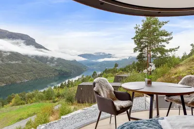 a room with a table and chairs and a view of a river at The Sognefjord Cabin 2 in Kaupanger