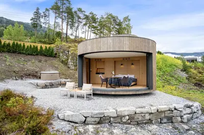 a circular house on a hill with a table and chairs at The Sognefjord Cabin 2 in Kaupanger