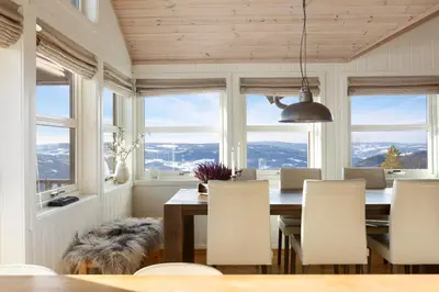 a dining room with a table and chairs and windows at Panoramautsikt i Valdres Perfekt for ski og fjellturer året rundt in Aurdal