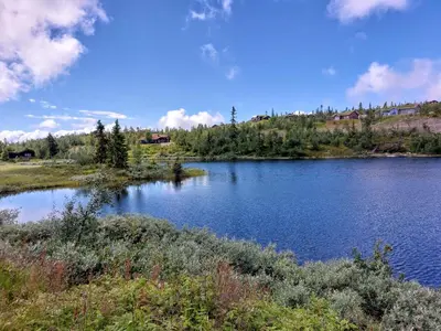 a view of a lake with a house in the background at Panoramautsikt i Valdres Perfekt for ski og fjellturer året rundt in Aurdal