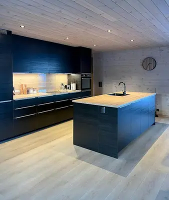 a large kitchen with blue cabinets and a sink at Fjord Cabin With Panoramic Views In Rauma in Innfjorden