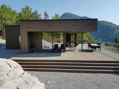 a house with a deck with a table and chairs at Fjord Cabin With Panoramic Views In Rauma in Innfjorden