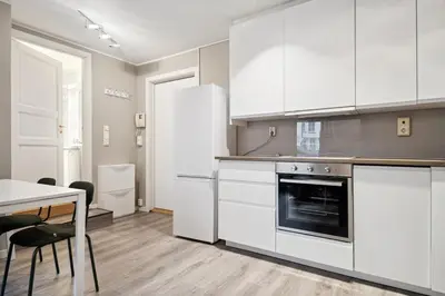 a kitchen with white cabinets and a table with chairs at Apt 500 m to Bryggen - Perfect location in Bergen