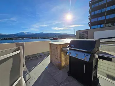 a grill on a balcony with a view of the water at Oceanview Apartment Aalesund in Ålesund