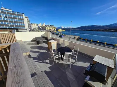 a balcony with chairs and a table and a view of the water at Oceanview Apartment Aalesund in Ålesund