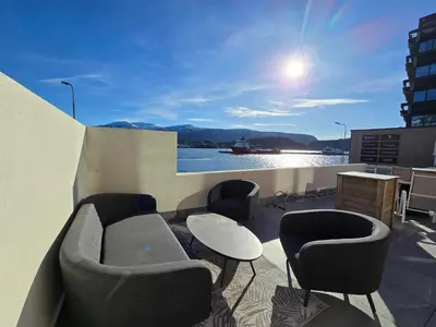 a balcony with a couch and chairs and a table at Oceanview Apartment Aalesund in Ålesund