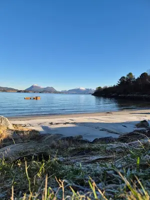 a beach with a large puddle of water on the shore at Nygjerdet Gossen in Gossa