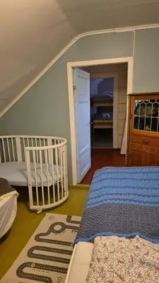 a bedroom with a crib and a bed in a room at Nygjerdet Gossen in Gossa