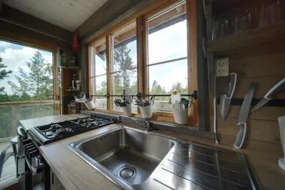 a kitchen with a sink and a stove and windows at Faråsen Luxury Treetop Cabin - Sleep Among the Trees in Ringsaker