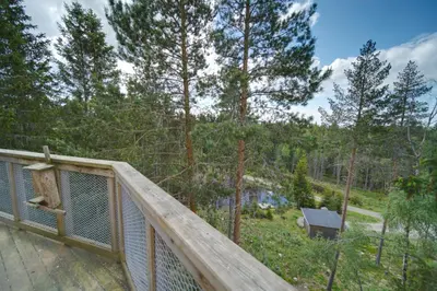 a wooden deck with a view of the woods at Faråsen Luxury Treetop Cabin - Sleep Among the Trees in Ringsaker