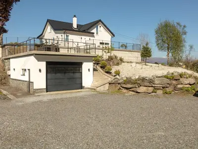 a white house with a garage and a stone wall at Hytte Hammarslandbakken in Bergen