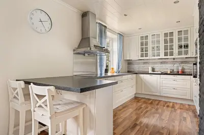 a kitchen with white cabinets and a clock on the wall at Trolltunga Fjord Living in Tysso