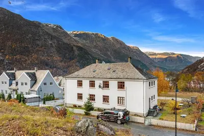 a white house with a car parked in front of it at Trolltunga Fjord Living in Tysso