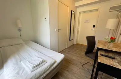 a small room with a bed and a desk and a chair at Jibben Hotell in Måløy