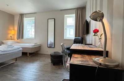 a living room with a room with a bed and a desk at Jibben Hotell in Måløy