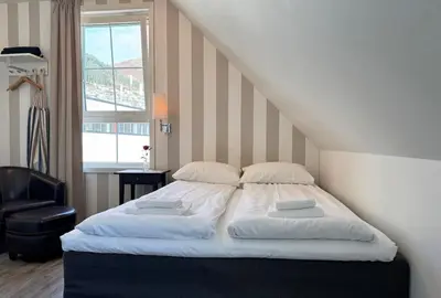 a bed with two pillows and a chair in a room at Jibben Hotell in Måløy
