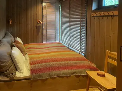 a bed with a striped blanket in a room with a window at 70S Architectural Cabin With Views In Hemsedal in Hemsedal