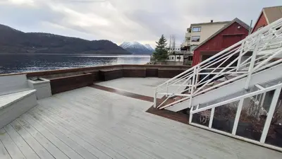 a wooden deck next to a body of water at Sjøhuset Sjøholt in Sjøholt