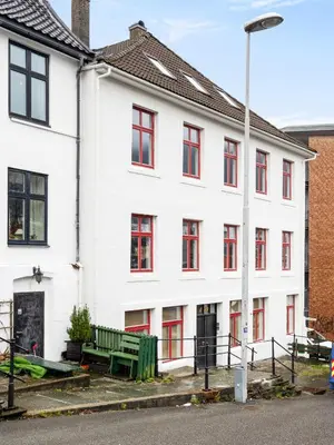 a white building with red windows and a green bench at Bergen Beds Apartments I Nordic Retreat in Bergen