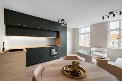 a kitchen with black cabinets and a wooden table at Bergen Beds Apartments I Nordic Retreat in Bergen