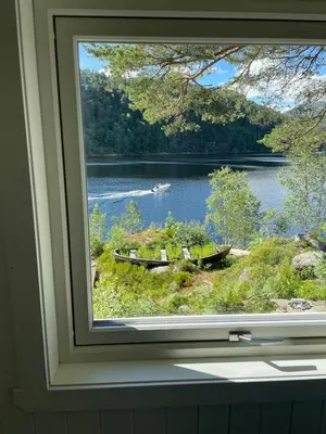 a window with a view of a lake and two boats at Beautiful Cottage by the Sea in Tysse