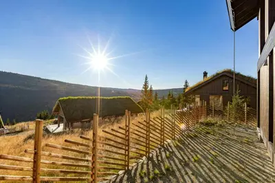 a fence in front of a house with the sun at Modern Cabin With Ski In Out At Kvitfjell in Favang