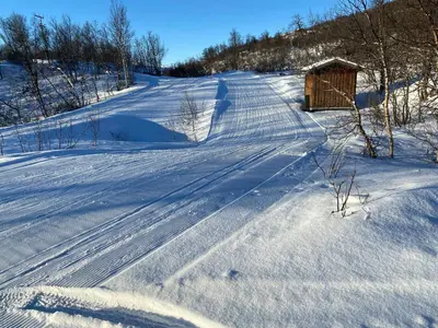 a snow covered road with a smallshed on the side at Traditional Cabin In Nøsterbølia in Uvdal