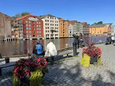 a group of people sitting on a bench near a river at Du vil elske å bo her! Et lite, men koselig sted med perfekt beliggenhet! in Trondheim
