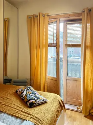 a bedroom with a bed and a window with yellow curtains at Du vil elske å bo her! Et lite, men koselig sted med perfekt beliggenhet! in Trondheim