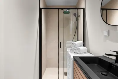 a bathroom with a glass shower and a sink at Bergen Beds Apartments I Urban Escape in Bergen
