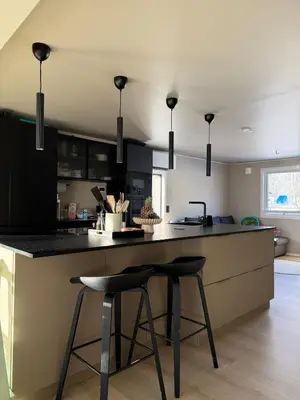 a kitchen with black cabinets and two bar stools at Stor enebolig med stor inngjerdet hage og lekestativ! Perfekt for barnefamilier in Jevnaker