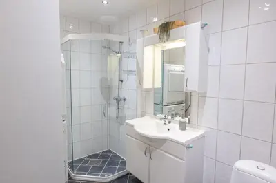 a white bathroom with a sink and a shower at Roomsly Apartments - Prime Location and Modern Comfort in Bergen