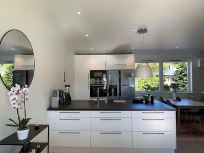 a kitchen with white cabinets and a dining room at Elegant Townhouse, Breathtaking Views and Free Parking in Ålesund