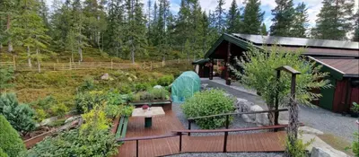 a house with a wooden deck in a garden at Cabin Room on DaVita Ranch in Tranhaug