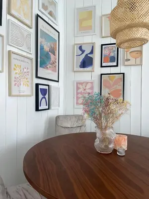 a dining room table with a vase of flowers on a wall with pictures at Modern and Cosy apartment in Bergen City Centre in Bergen