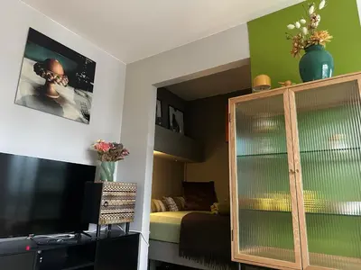 a room with a bedroom with a bed and a tv at Stylish free parking Studio central with balcony in Ålesund