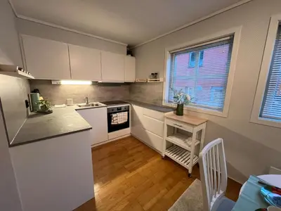 a small kitchen with white cabinets and a table at Cozy flat in the heart of Bergen in Bergen